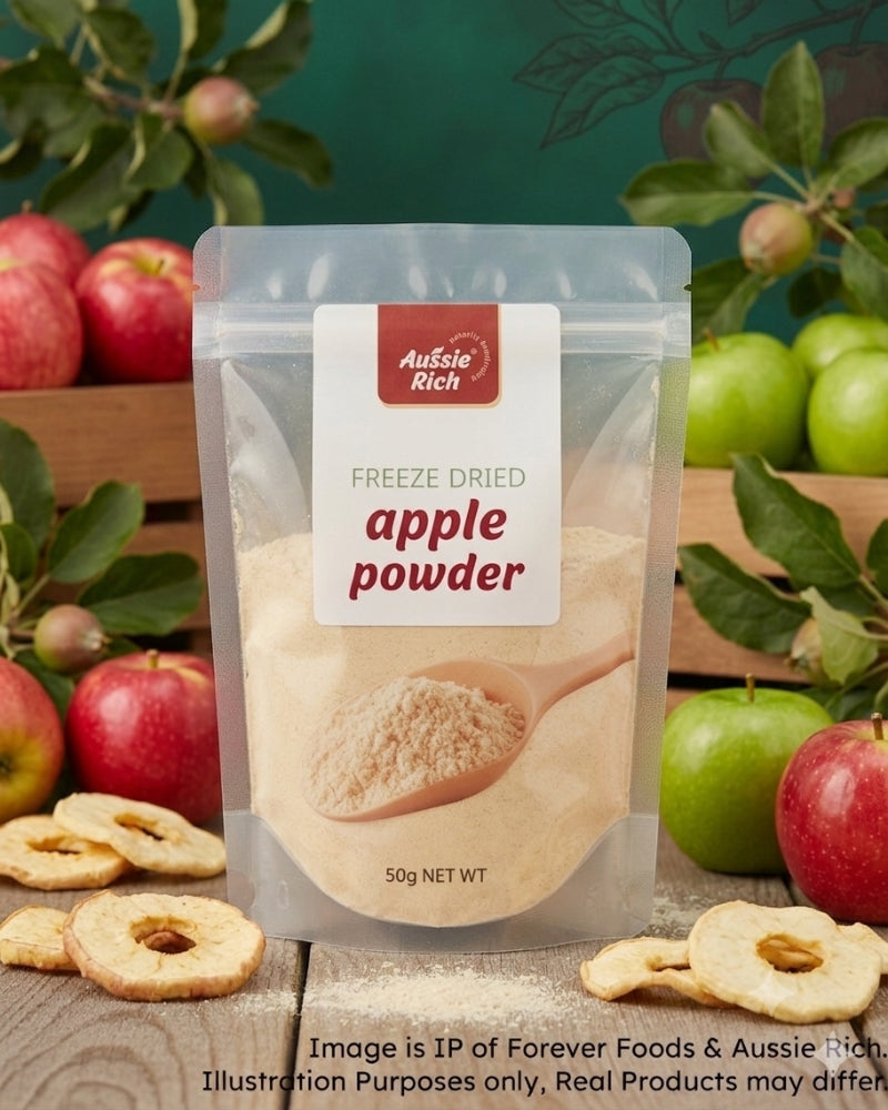 A stand-up pouch of Aussie Rich Freeze Dried Apple Powder, surrounded by fresh red and green apples, dried apple slices, and a dark green background with leafy branches.