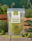 A stand-up pouch of Aussie Rich Freeze Dried Broccoli Powder, surrounded by fresh broccoli florets and green leaves on a wooden surface, with a dark green background.