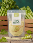 A 50g stand-up pouch of Aussie Rich Freeze Dried Celery Powder, displayed on a wooden surface with fresh celery stalks and leaves in the background.