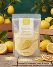 A stand-up pouch of Aussie Rich Freeze Dried Lemon Powder, surrounded by fresh lemons, lemon slices, and wooden crates on a rustic wooden table. The pouch is clear, showing the pale yellow powder inside, with a white and yellow label.
