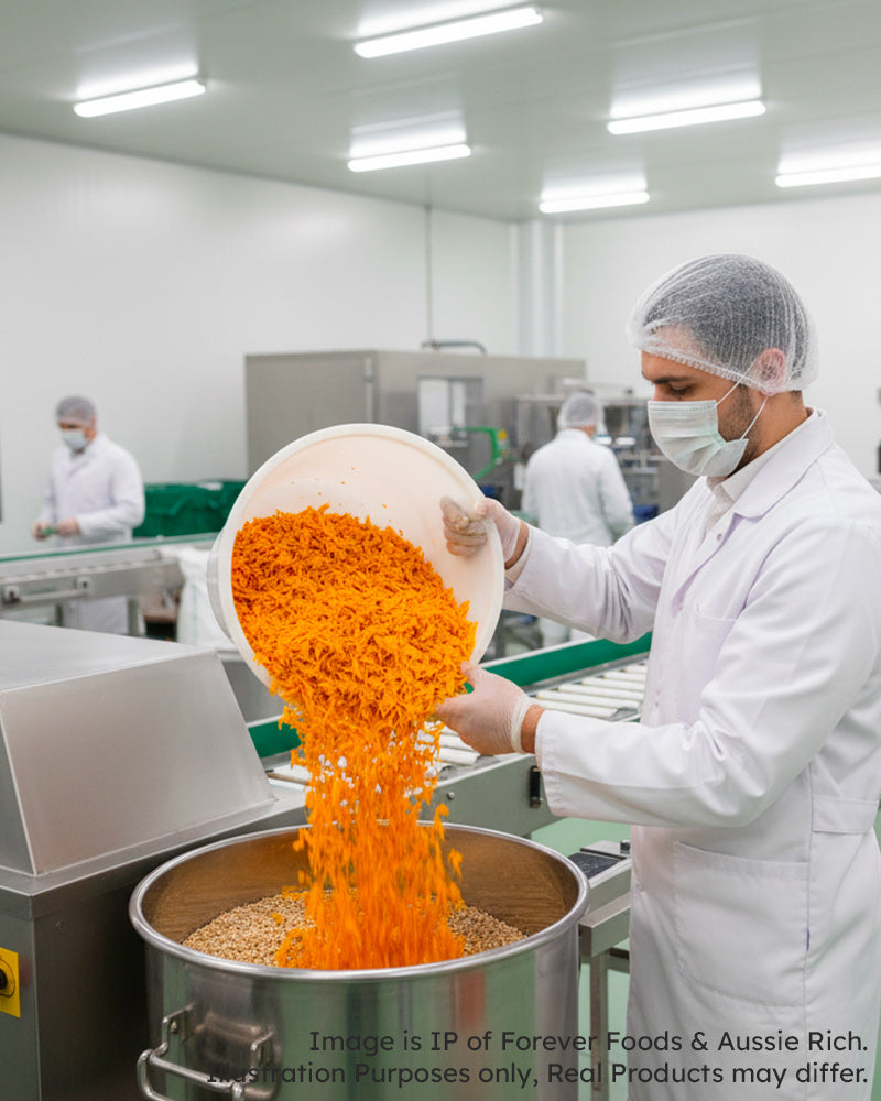 Person in a food processing facility pouring freeze dried pumpkin into a large metal container.
